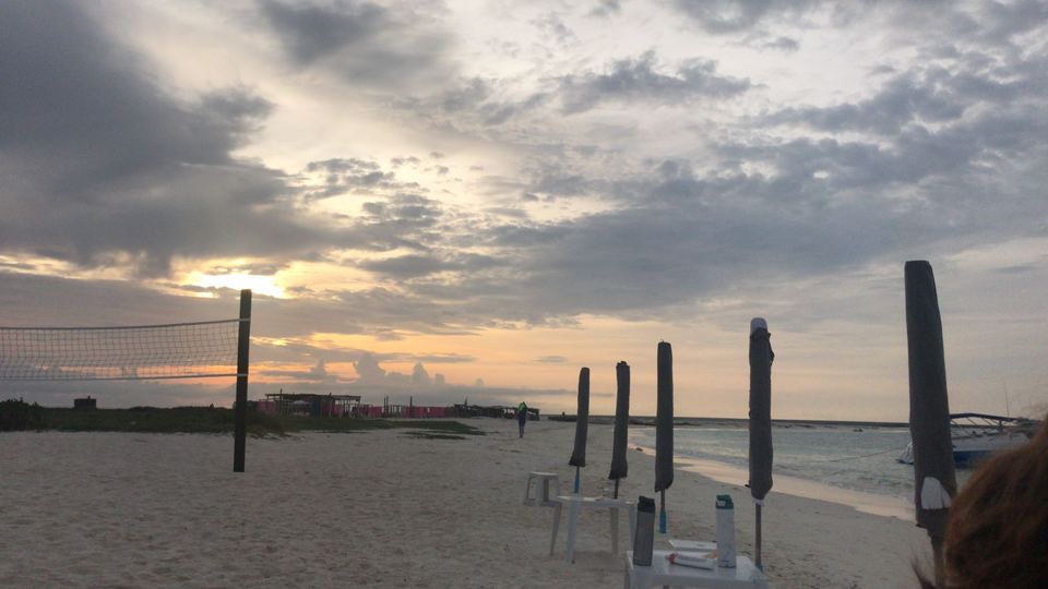 Cielo nublado al atardecer sobre la playa, con postes de toldos